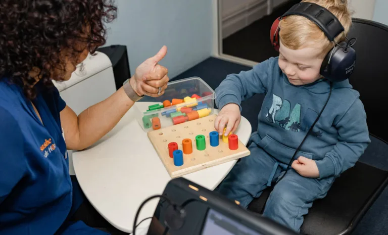 A child playing with colored blocks while undergoing a hearing test at South Australia Speech and Hearing Centre