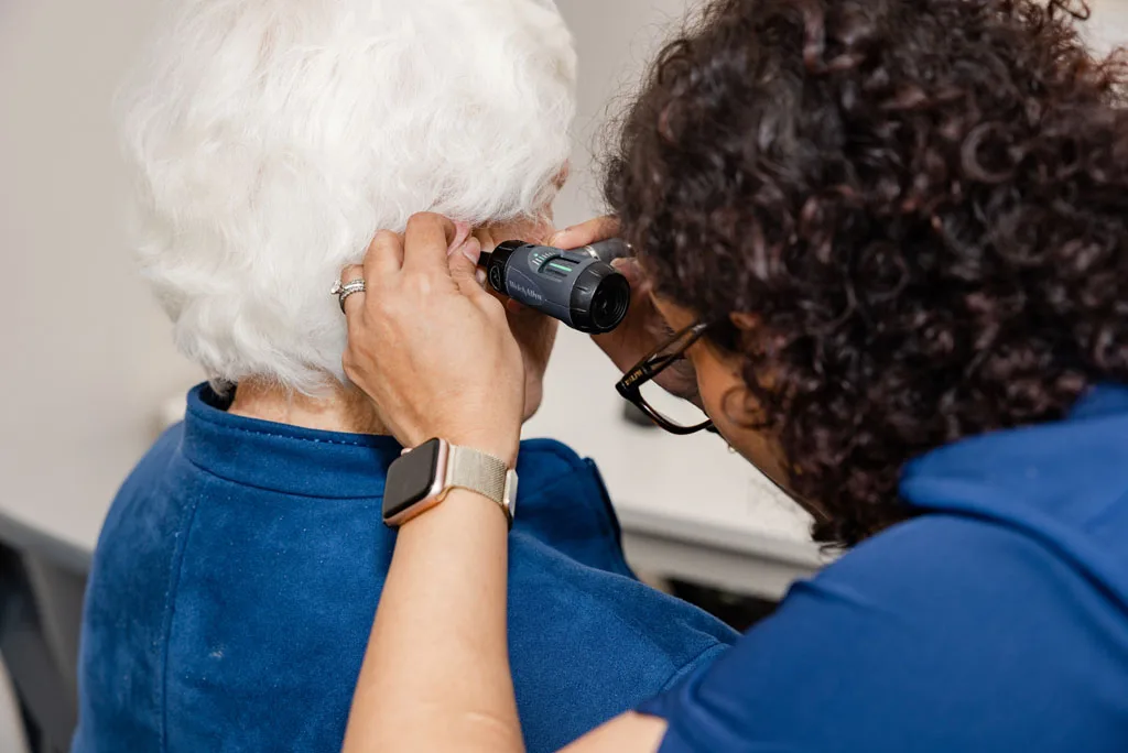 Independent audiologist examining a patient's ear before recommending hearing aids