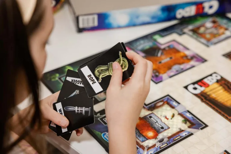 A speech therapy patient holding Cluedo cards during an interactive session, showcasing engaging techniques used by speech pathologists at SASHC