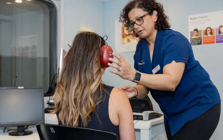 An audiologist placing a headset over a patient’s ears for a hearing test at South Australia Speech and Hearing Centre