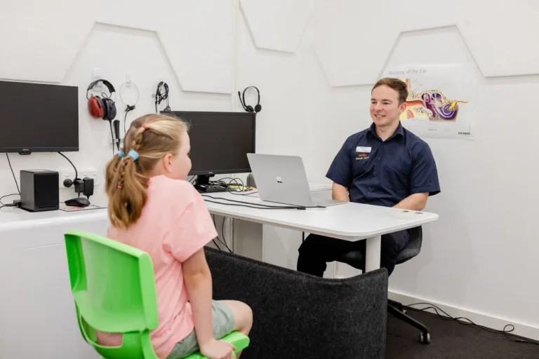 A child sitting across from an audiologist during a hearing test at South Australia Speech and Hearing Centre