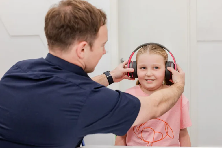 An audiologist placing a headset on a child for a hearing test at South Australia Speech and Hearing Centre