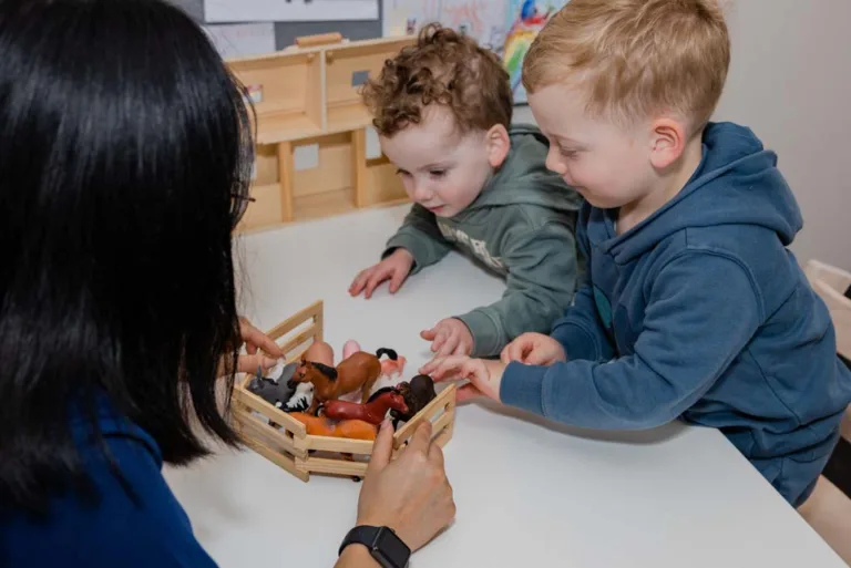Two children receiving speech therapy through play with farm animal figures, facilitated by a speech therapist at South Australia Speech and Hearing Centre