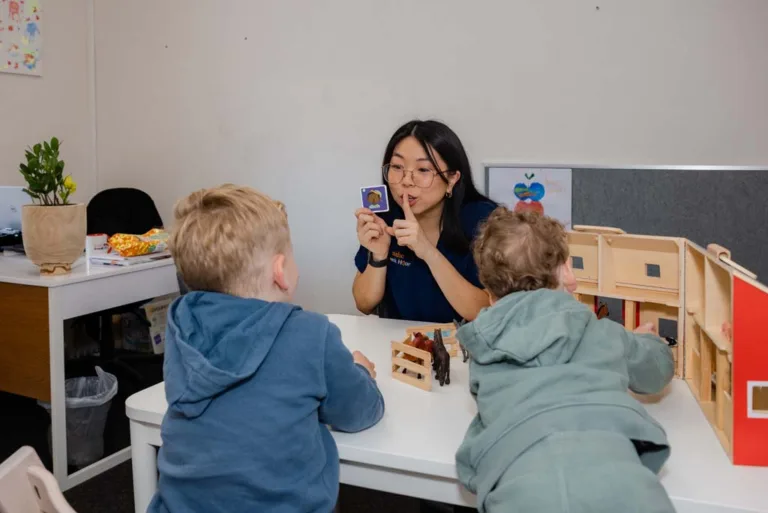 A speech therapist showing a flash card to two children during a speech therapy session at South Australia Speech and Hearing Centre