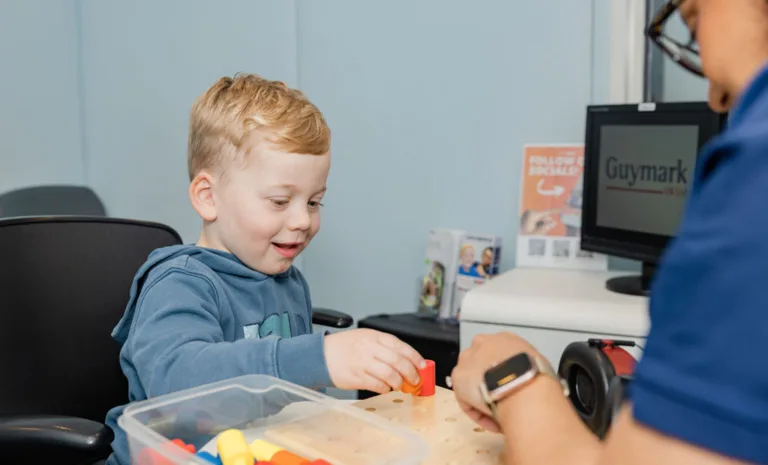 An audiologist and a child playing with colored blocks during a hearing test at South Australia Speech and Hearing Centre